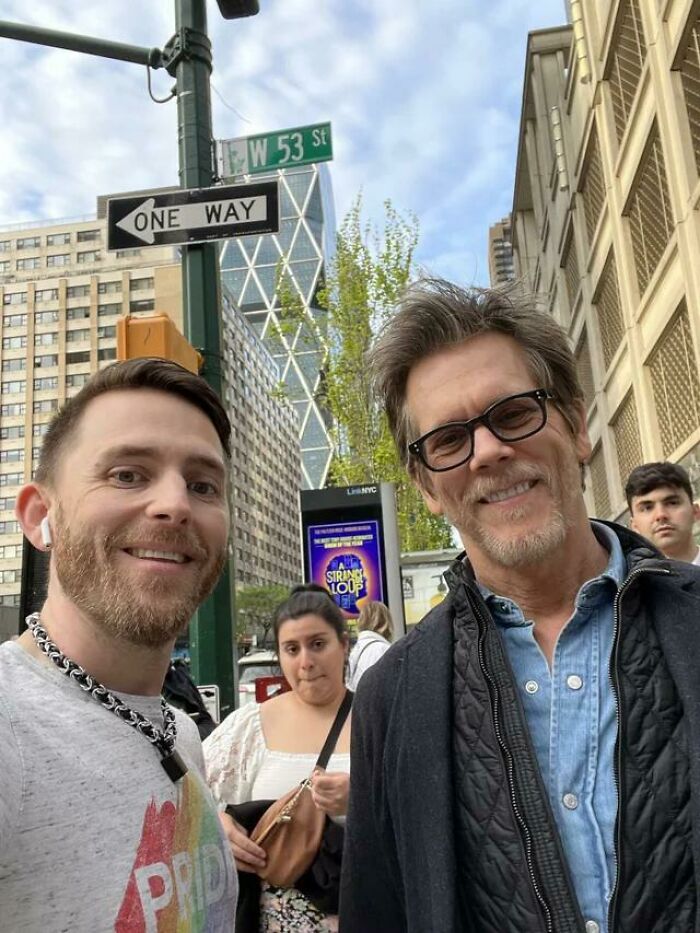 A fan smiles taking a selfie with actor Kevin Bacon on a New York City street. A celebrity encounter photo.