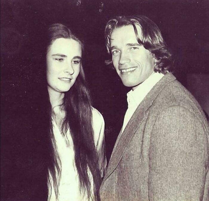 A vintage photo of Arnold Schwarzenegger with a woman, smiling. A classic celebrity encounter snapshot.