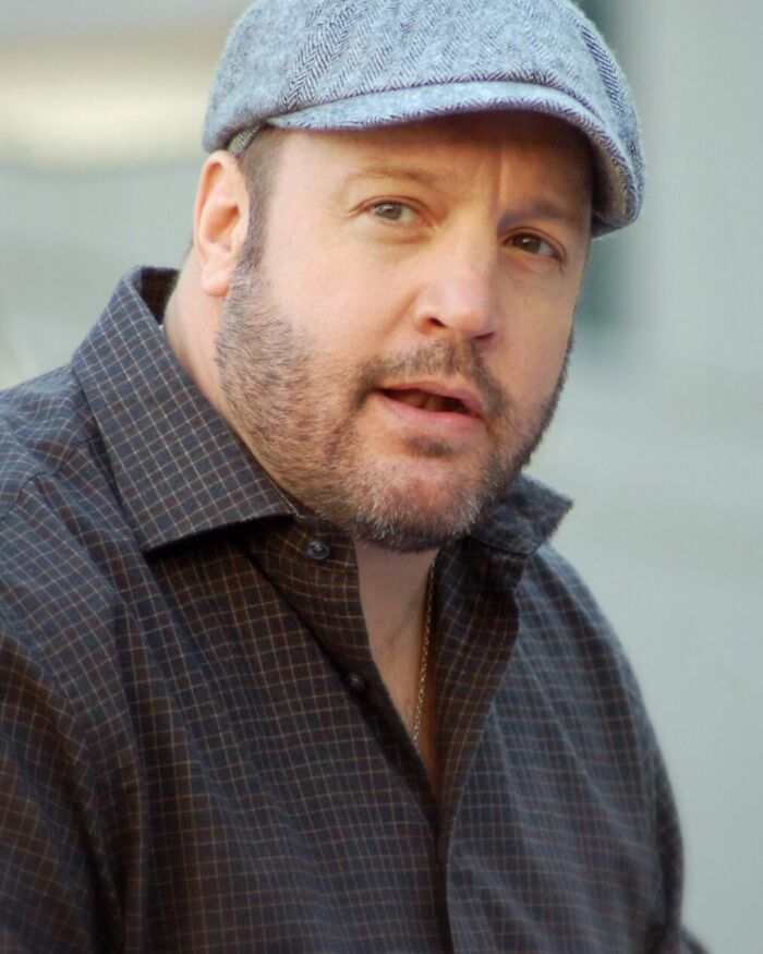Kevin James, wearing a grey flat cap and a checkered shirt, looks directly at the camera. Bio and career highlights.