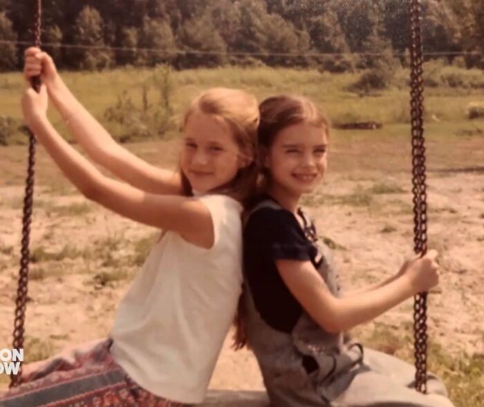 Two young girls sitting back-to-back on a swing set illustrating early celebrity friendships