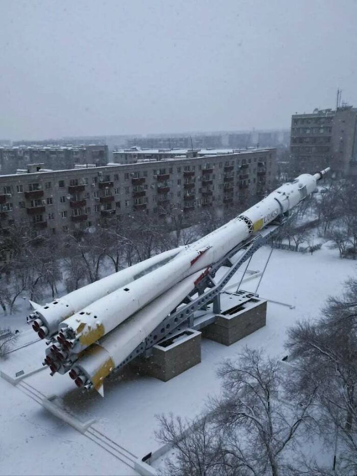 Snow-covered urban hell with rocket monument in bleak city landscape