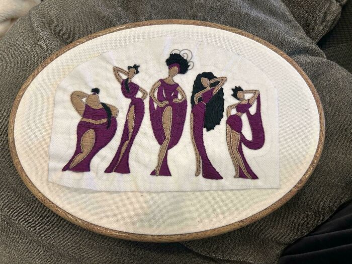 An embroidery project of five purple-dressed muses in a wooden hoop