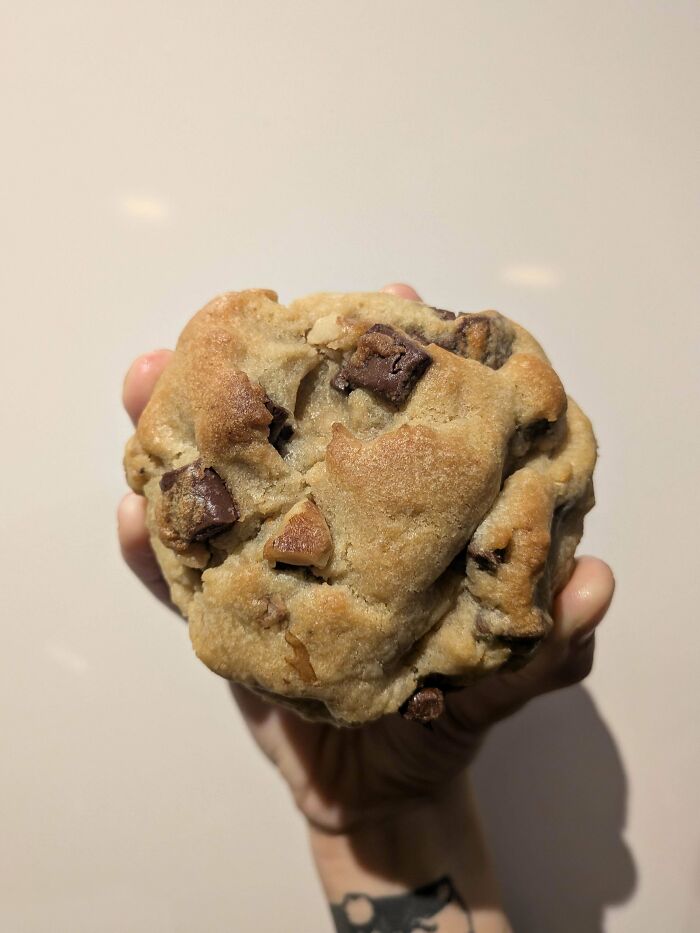 Hand holding thick chocolate chip cookie dessert close up