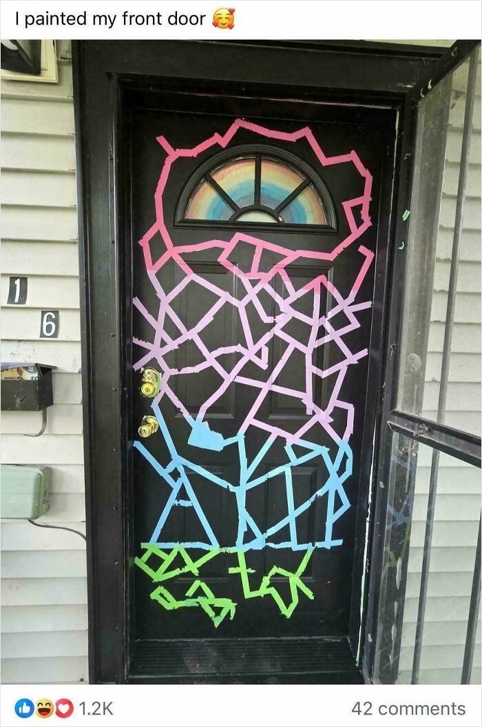 A black front door with a rainbow semicircle window painted with geometric patterns in pink, blue, and green, a DIY project.