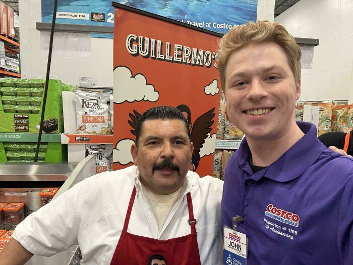 A man with a mustache in a red apron and a smiling Costco employee, a celebrity encounter at a grocery store.