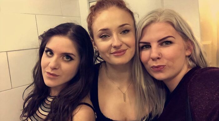A celebrity (Sophie Turner, center) and two other women pose for a close-up selfie, showing celebrity encounters.