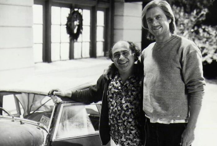 Black and white photo of two friends smiling near a car highlighting celebrity friendships