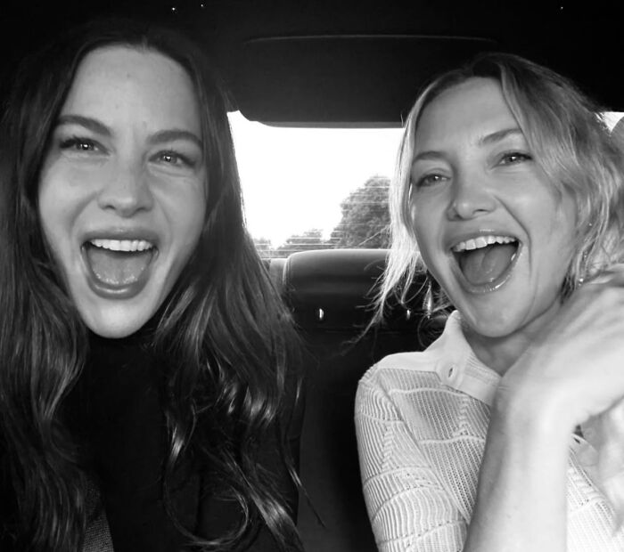 Black and white image of two friends laughing in car