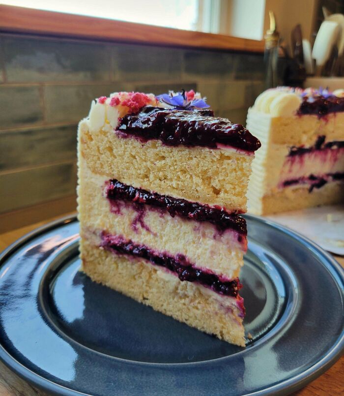 Slice of vanilla cake with berry filling and frosting on a plate