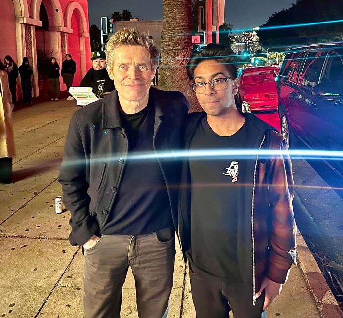 Willem Dafoe smiles next to a fan, captured in one of many wild photos of celebrity encounters.