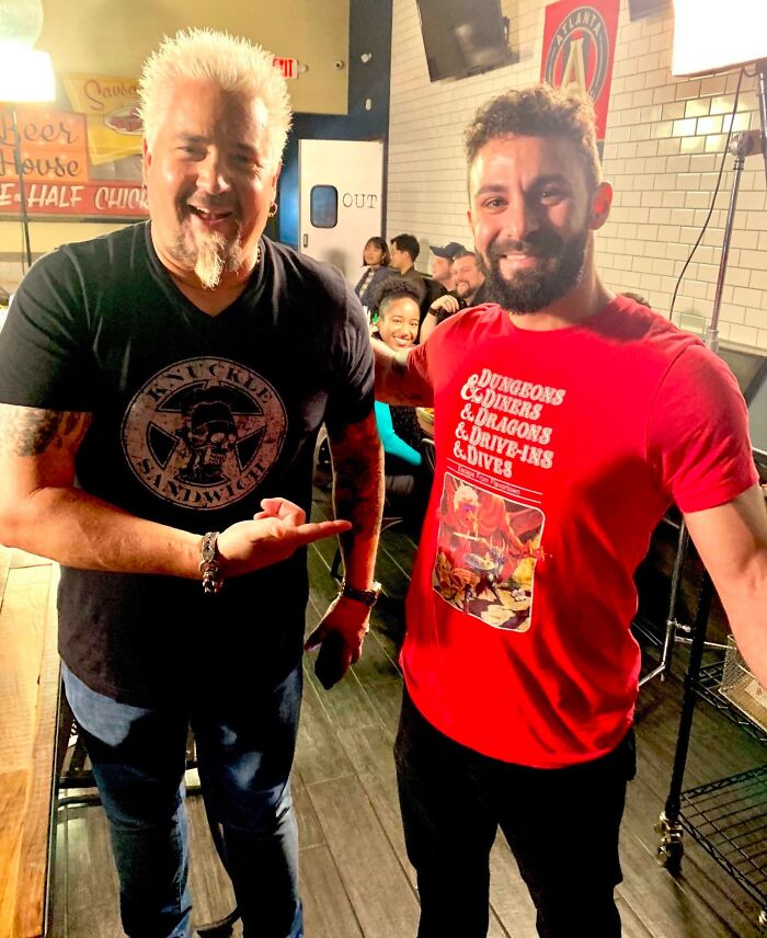 Guy Fieri and a fan smile, capturing a celebrity encounter. Fieri points, illustrating a wild photo moment.