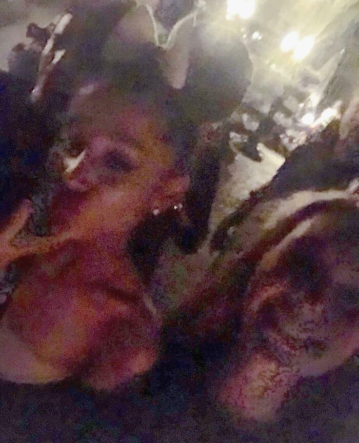 A blurry, close-up photo of two people, possibly a celebrity encounter, with faint party lights in the background.