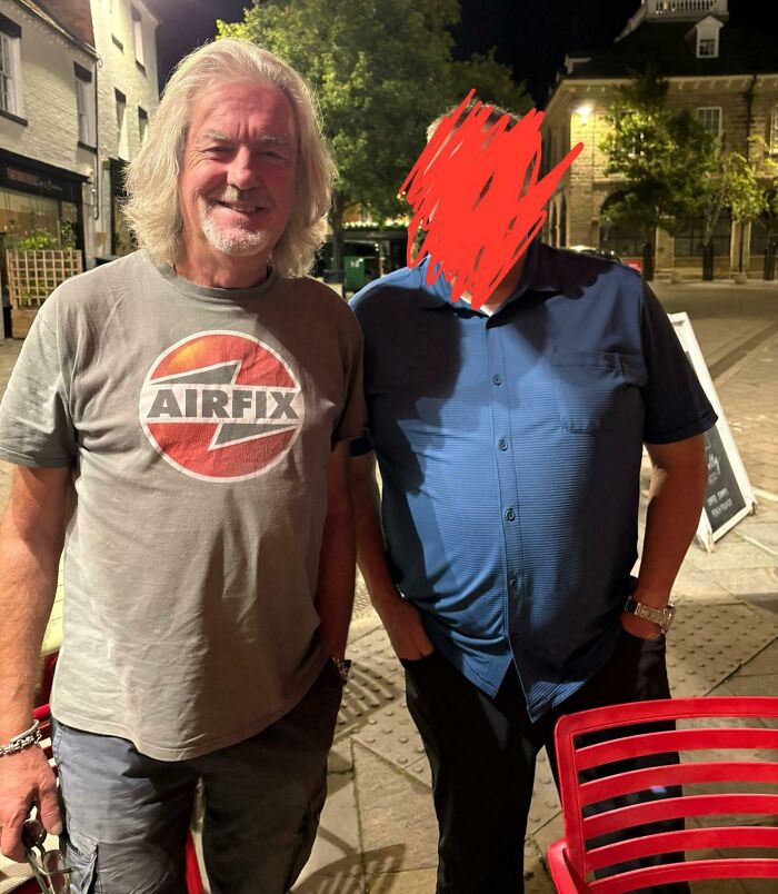 A smiling man with long gray hair and an Airfix shirt next to a person with a blurred face. Wild photos of celebrity encounters.