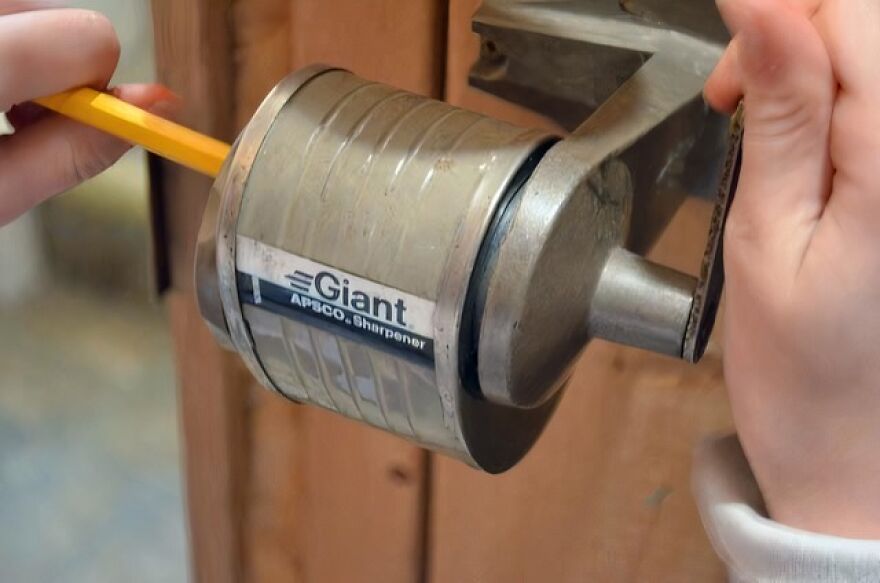A person's hands using a vintage Giant Apsco Sharpen pencil sharpener, a trip down memory lane for many.