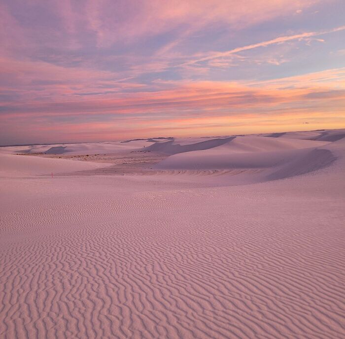 Soft pink and purple hues wash over a vast desert landscape at sunset, creating a gentle reset for your day.