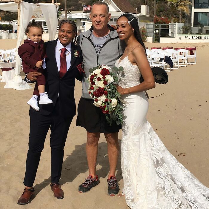 Wild photos of celebrity encounters: Tom Hanks in casual attire poses with a couple and baby at a beach wedding.