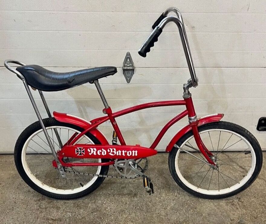 A classic red Red Baron bicycle with ape hanger handlebars and banana seat, taking a trip down memory lane.