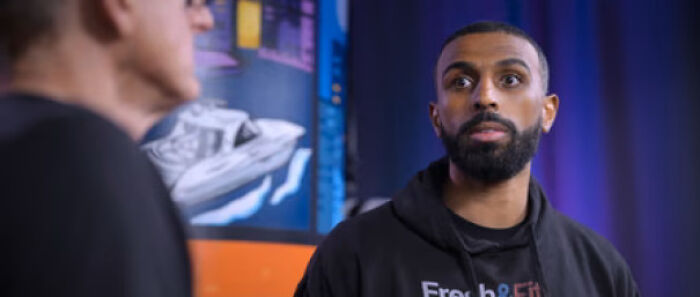 A man with a beard wearing a black hoodie with 'Fresh & Fit' logo, looking surprised, part of nonsensical movie details.