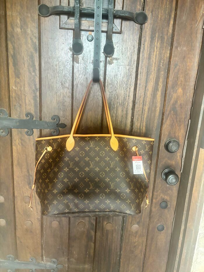 Louis Vuitton tote bag with monogram canvas hanging on a wooden door, a great thrift store jackpot.
