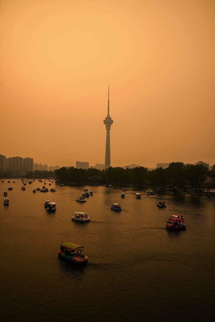 Urban hell skyline with tower and boats on river under orange sky