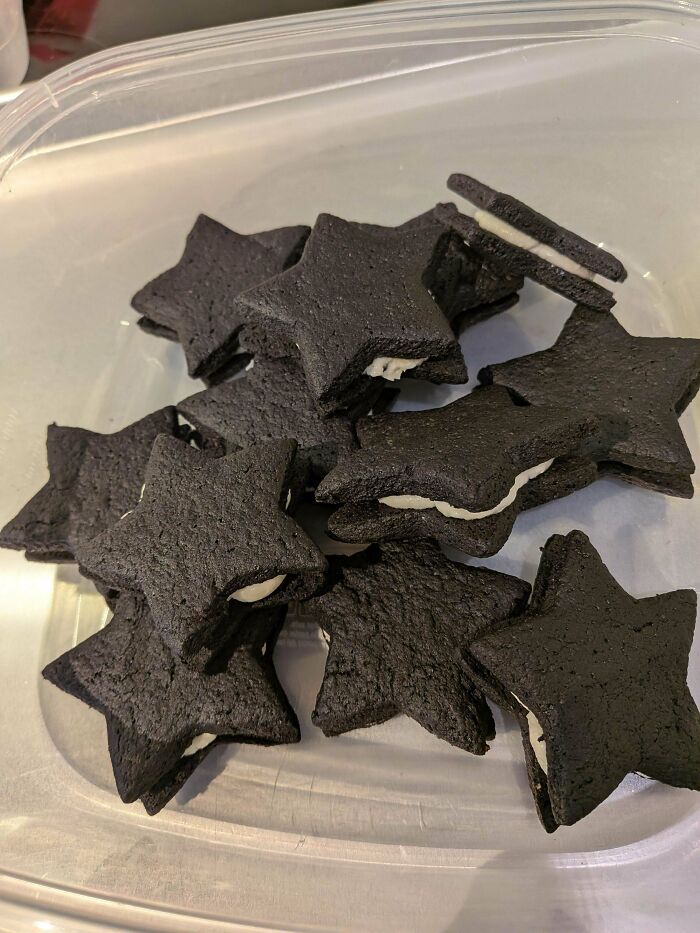 Black star-shaped sandwich cookies with cream filling in a container
