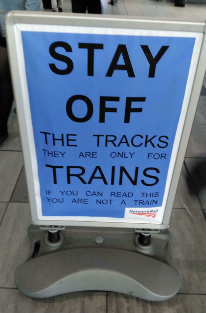 Humorous British sign warning to stay off train tracks if you can read