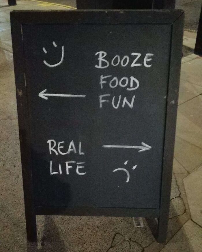 Chalkboard sign humorously contrasting booze food fun with real life