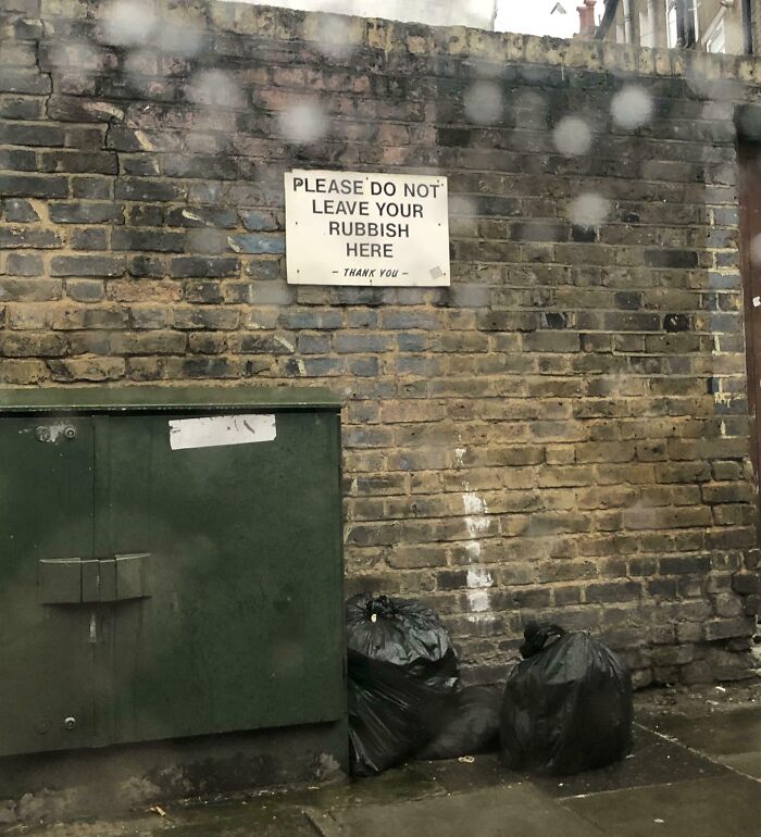 Funny British sign asking people not to leave rubbish here on brick wall