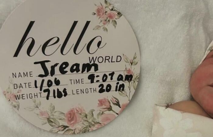 A baby's birth announcement sign, decorated with roses, reads "hello world," with the name "Jream." Parents didn't think straight.