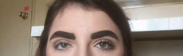 A woman's face, one eye with mascara and defined brow, the other bare. A clear beauty disaster visual.