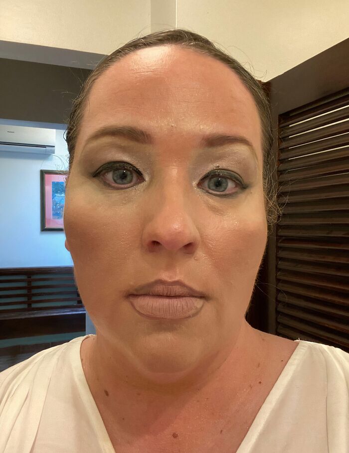 A woman with poorly applied, cakey makeup and over-lined n**e lips, showcasing a beauty disaster.