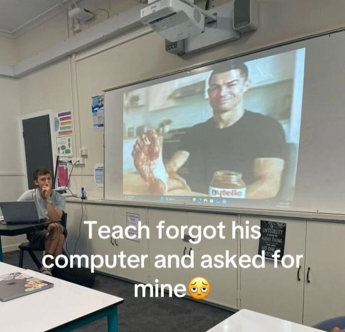 A student looks shocked as a projector displays an unhinged image of a man eating Nutella with his foot. Hilarious random pic!