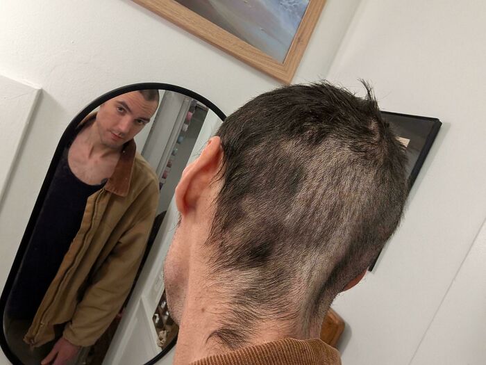 Man looks in mirror, showing a very uneven haircut on the back of his head, a true beauty disaster.