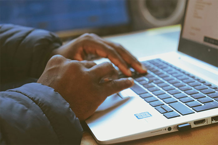 Hands typing on a laptop keyboard, illustrating a story about an ex-girlfriend cheating and demanding removal from a wedding.