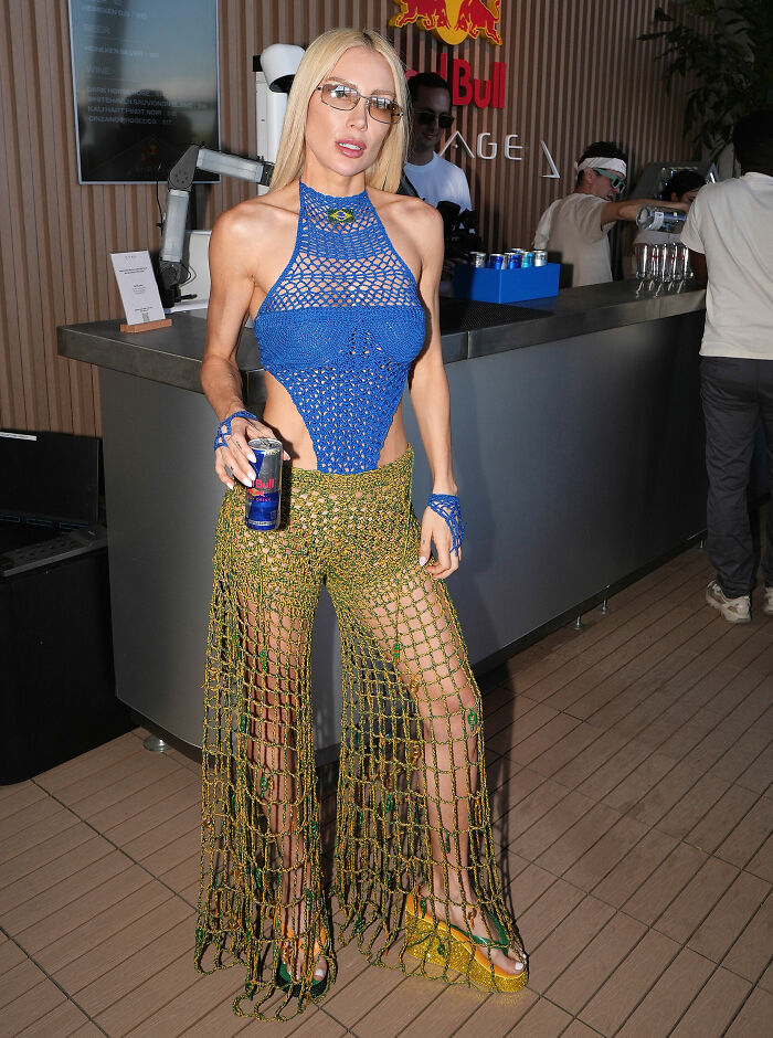 Fashion fail at Coachella 2026 with a woman wearing bold crochet top and pants holding a Red Bull can indoors.