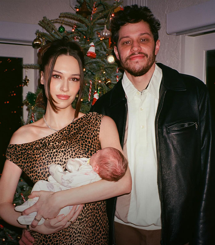 Pete Davidson with family, standing near Christmas tree, highlighting topics about adult content and having a daughter.