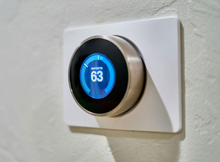 Close-up of a smart thermostat displaying 63 degrees, a subtle move in revenge against toxic bosses.