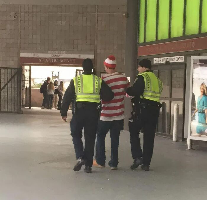 Two transit police escort a man dressed as Waldo, a weird image that made people go hmmm.