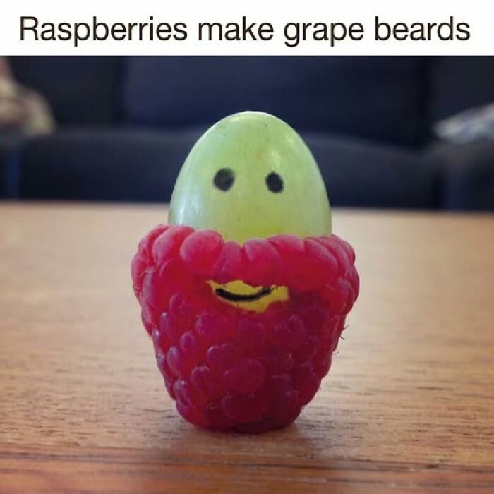 Grape with a raspberry beard and drawn-on eyes and mouth, a funny example of food memes with quick chuckles.