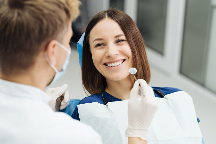 Patient smiling at dentist during checkup, highlighting random facts people learned about their bodies at the doctor.