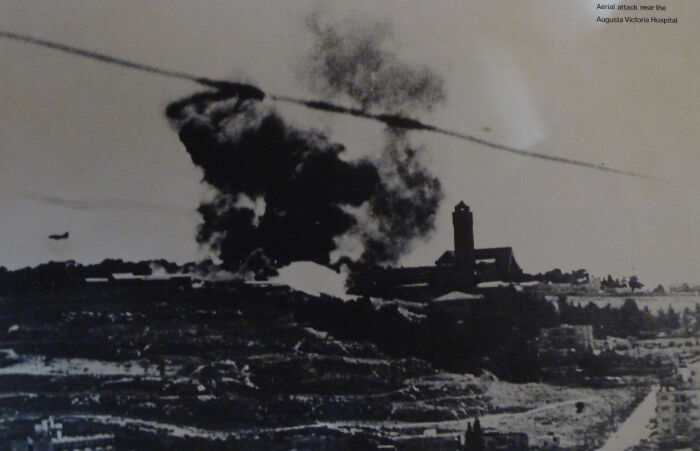 Aerial attack near Augusta Victoria Hospital showing a large explosion and smoke, depicting historical events from 1960 to 2010.
