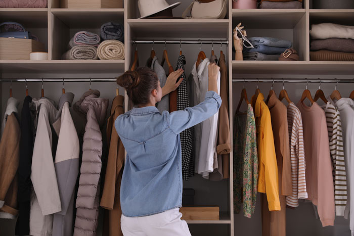 Woman organizing clothes in a closet, illustrating things women are tired of explaining to men about understanding.