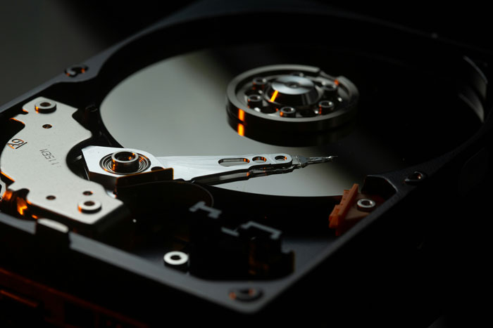Close-up of a computer hard drive showing internal disk and arm, symbolizing petty karma in manager and boss conflicts.