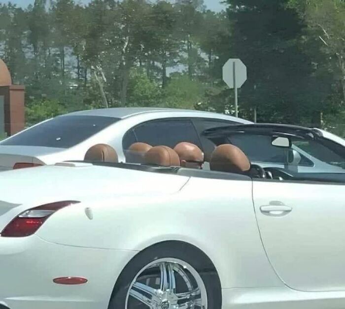 A white convertible with oddly shaped brown headrests that resemble buns, making a weird image that lives rent-free.