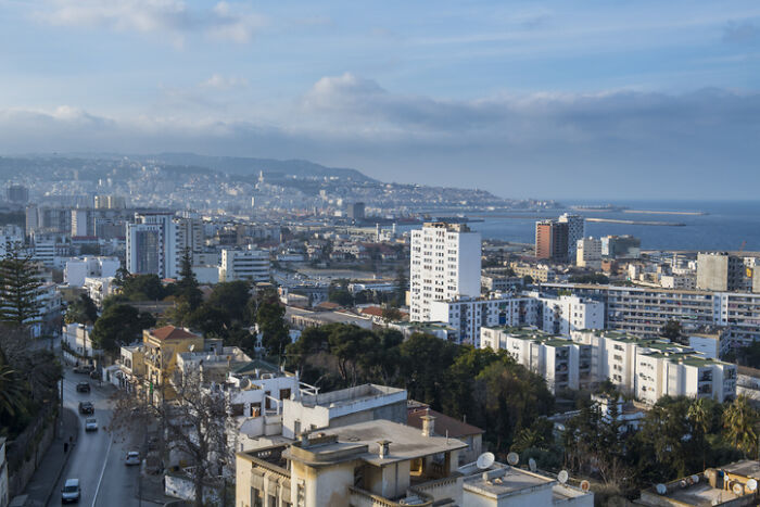 An aerial view of a bustling coastal city with many buildings and a distant sea, representing countries with worst work-life balance.