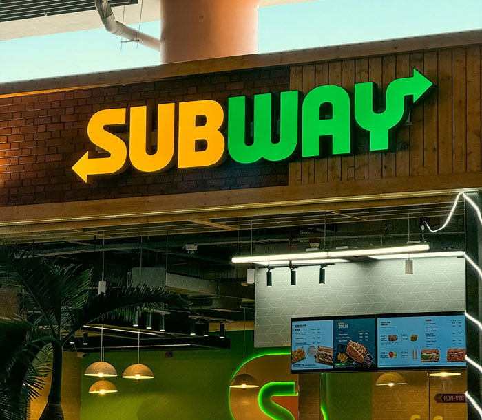 A Subway restaurant entrance with its iconic yellow and green logo. Learn world facts about global brands like Subway.