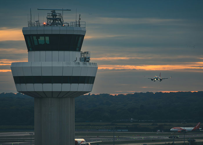 An airport control tower at sunset, with an airplane approaching for landing. People get exclusive access to places like this.