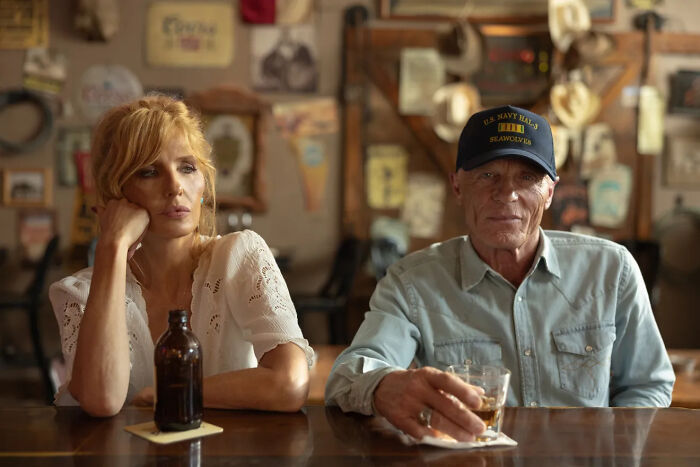 Beth Dutton and Rip Wheeler in a Dutton Ranch bar. Beth looks pensive, while Rip holds a drink.