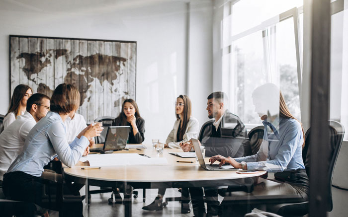 Business team in a meeting room discussing strategies with laptops and notes, capturing unhinged and wild ways women make men uncomfortable.