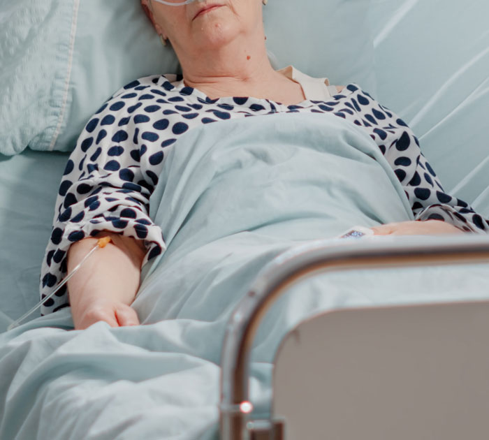 Elderly patient lying in hospital bed with an IV, representing moments when oversleeping turns into a nightmare.
